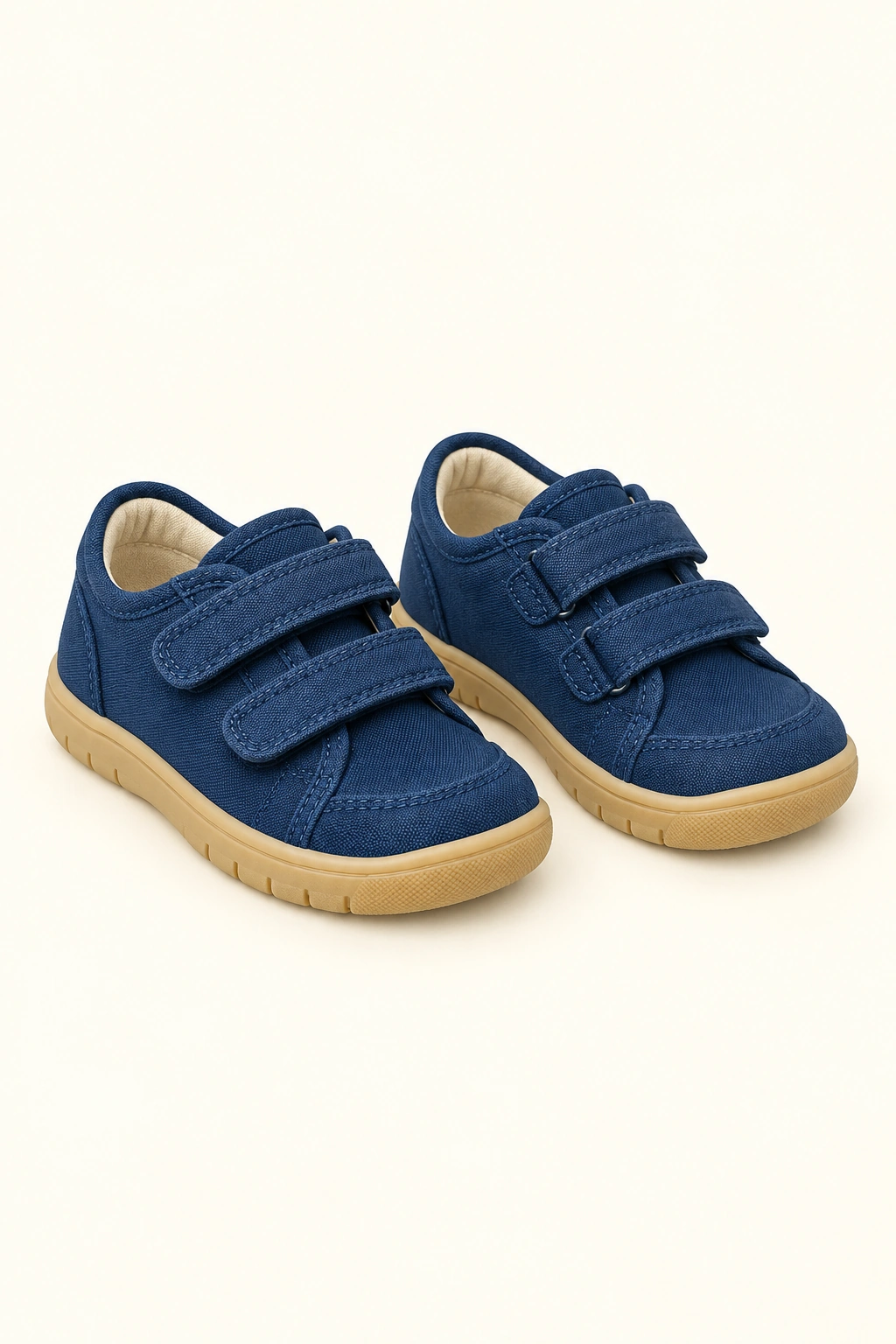 Ein Paar dunkelblaue Kinder-Halbschuhe mit Klettverschlüssen und hellen Sohlen steht vollständig sichtbar vor hellem Hintergrund.